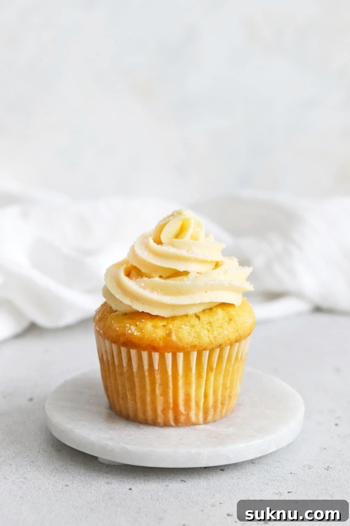 gluten-free vanilla cupcake topped with vanilla buttercream and pink sanding sugar sprinkles
