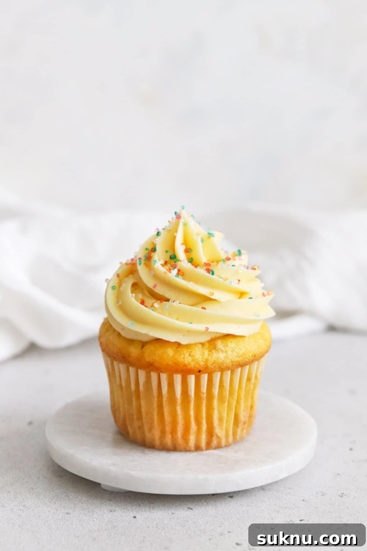gluten-free vanilla cupcake topped with vanilla buttercream and multicolor sparkling sugar sprinkles