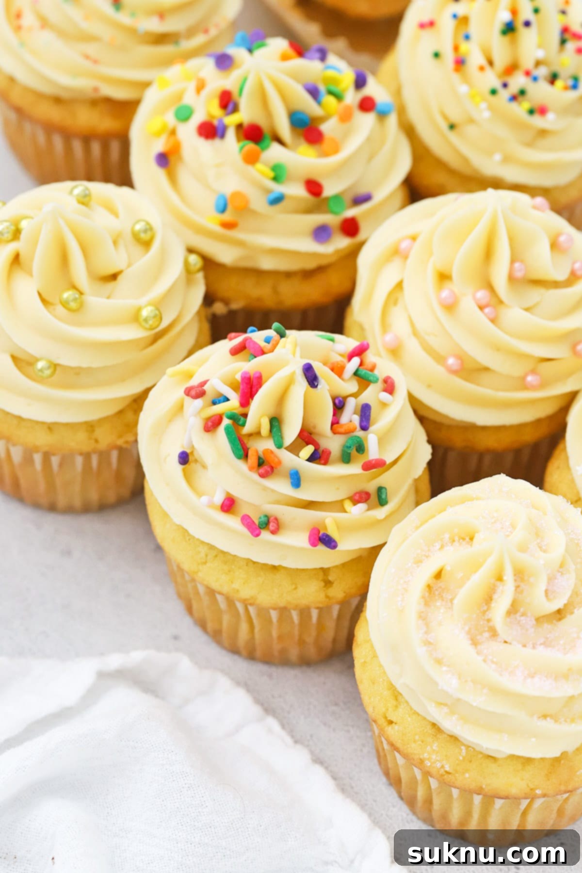 Front view of gluten-free vanilla cupcakes topped with vanilla buttercream and different kinds of sprinkles