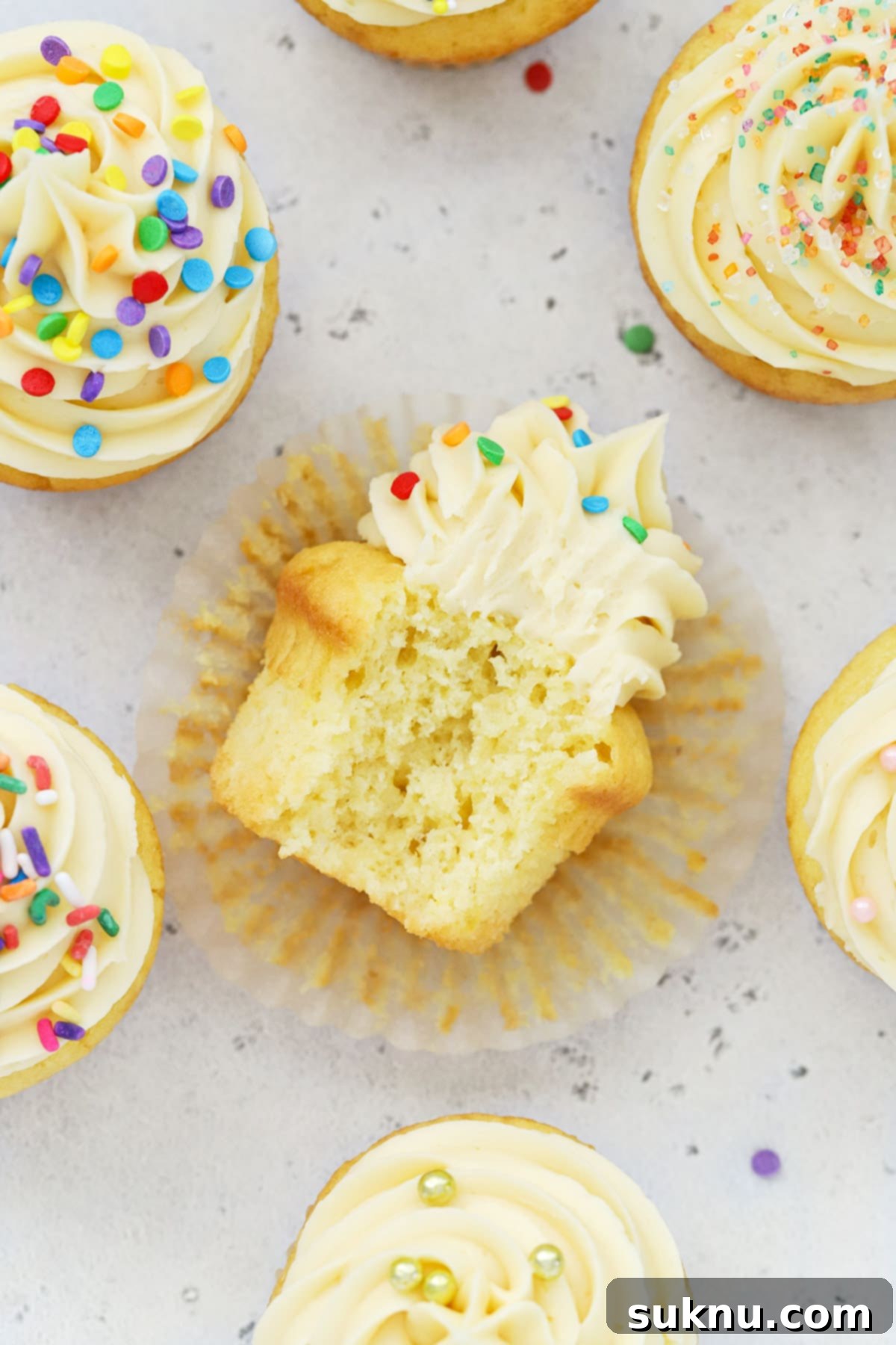 Overhead view of gluten-free vanilla cupcakes topped with vanilla buttercream and different kinds of sprinkles