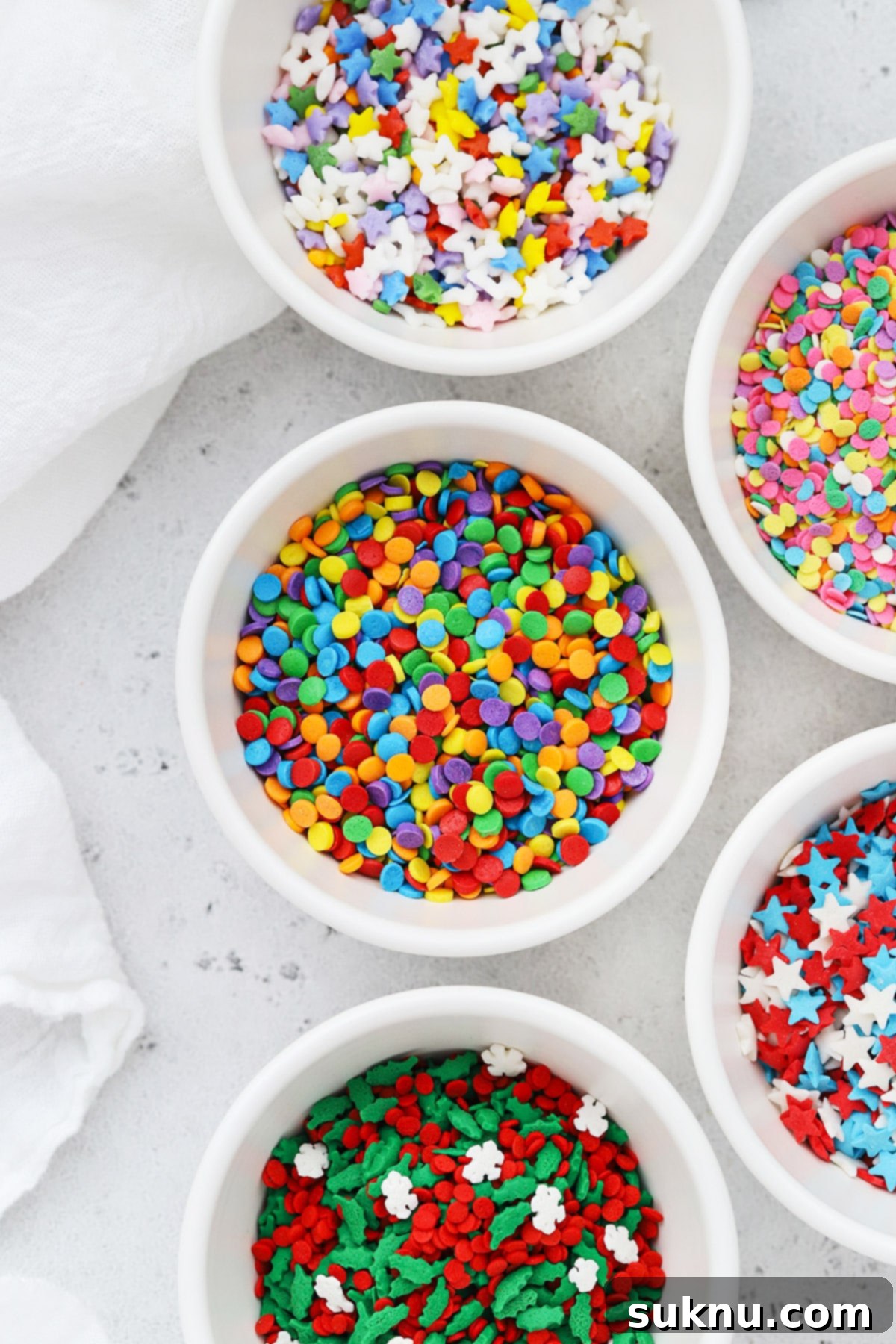Different kinds of colorful quins sprinkles in white bowls