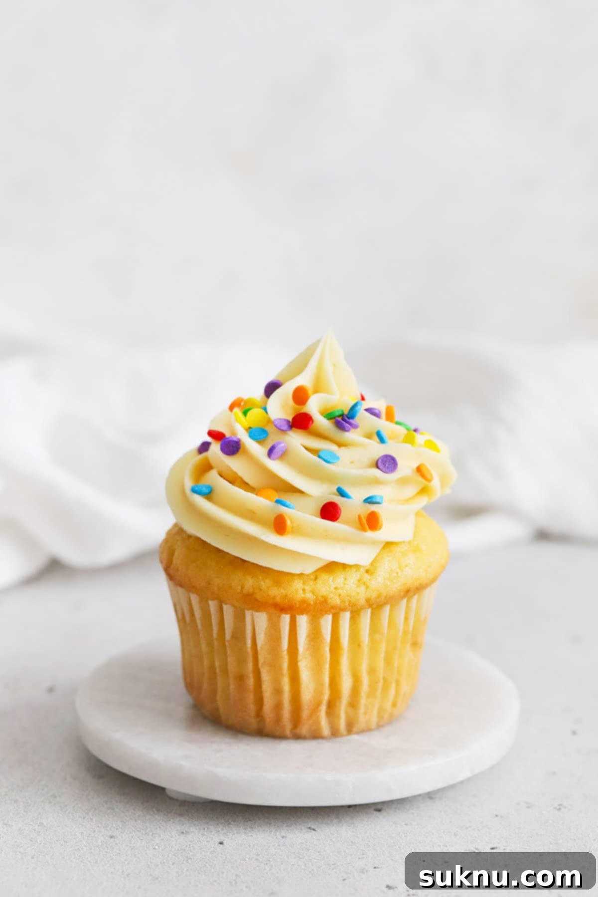 gluten-free vanilla cupcake topped with vanilla buttercream and rainbow quins confetti sprinkles