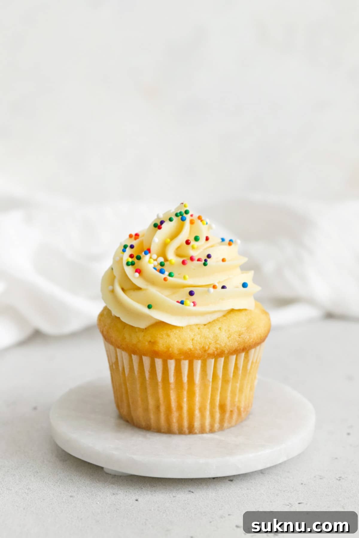 gluten-free vanilla cupcake topped with vanilla buttercream and nonpareils sprinkles
