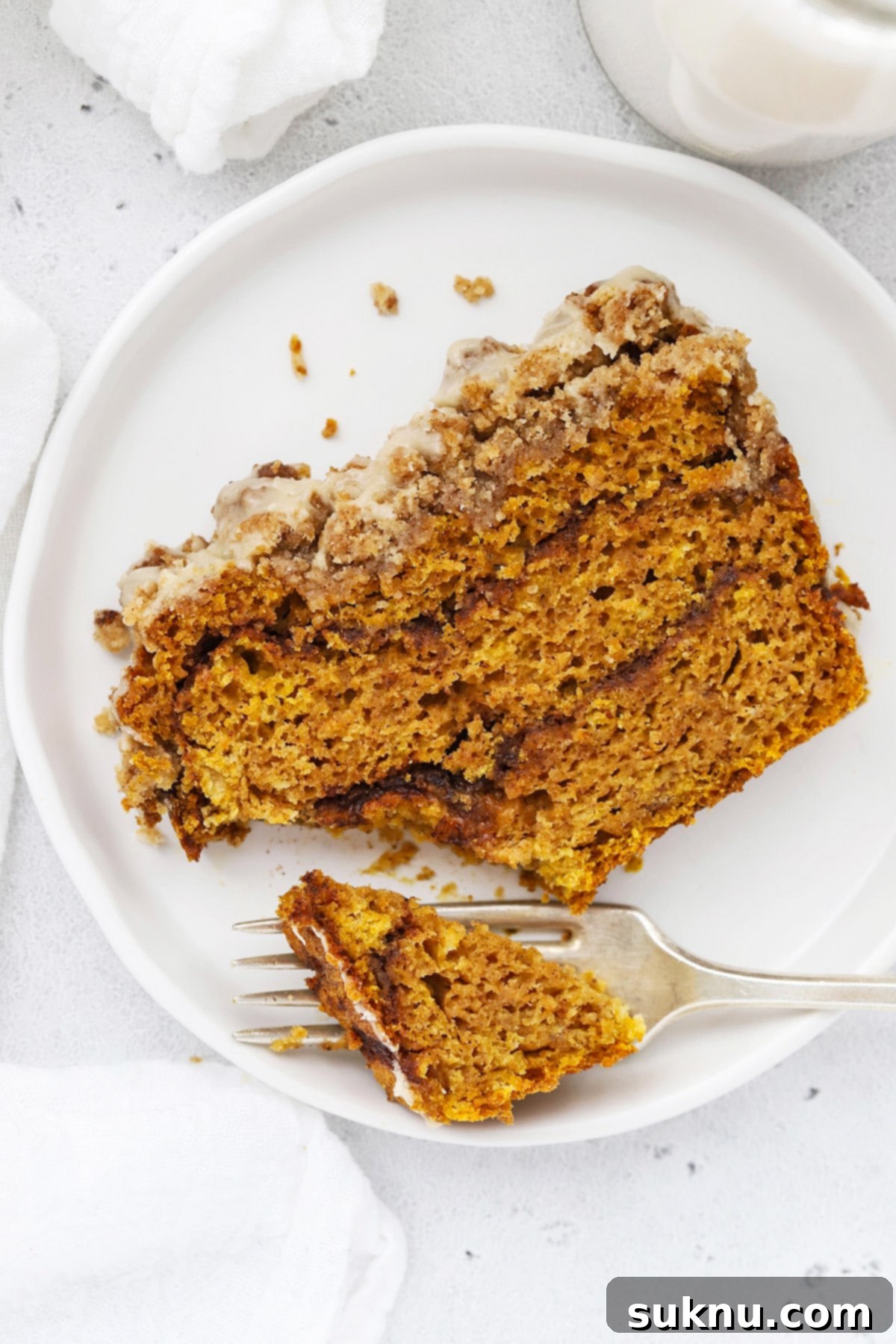 Overhead view of several slices of gluten-free cinnamon swirl pumpkin bread with streusel topping and maple glaze artfully arranged on a cutting board, ready to serve.