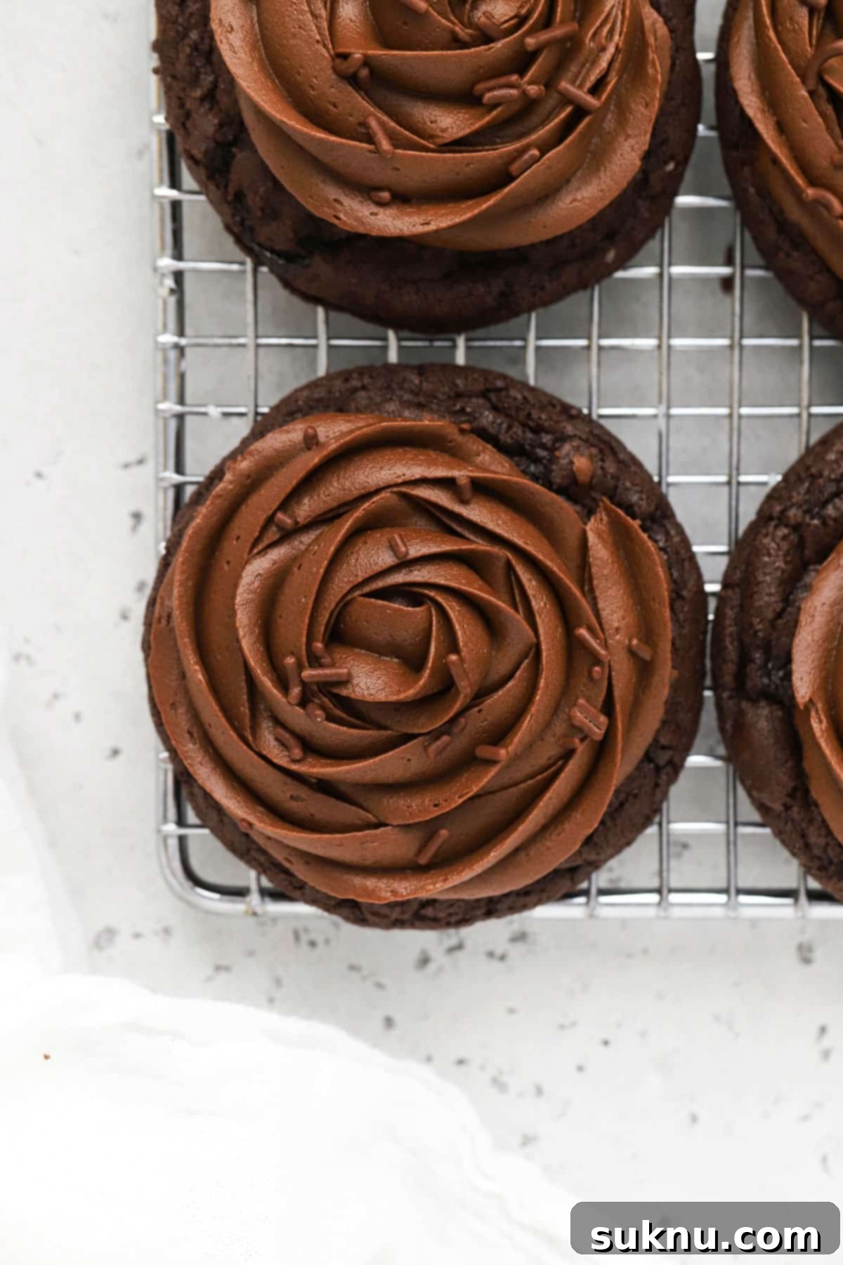Close-up of a gluten-free chocolate cookie being frosted with a piping bag.