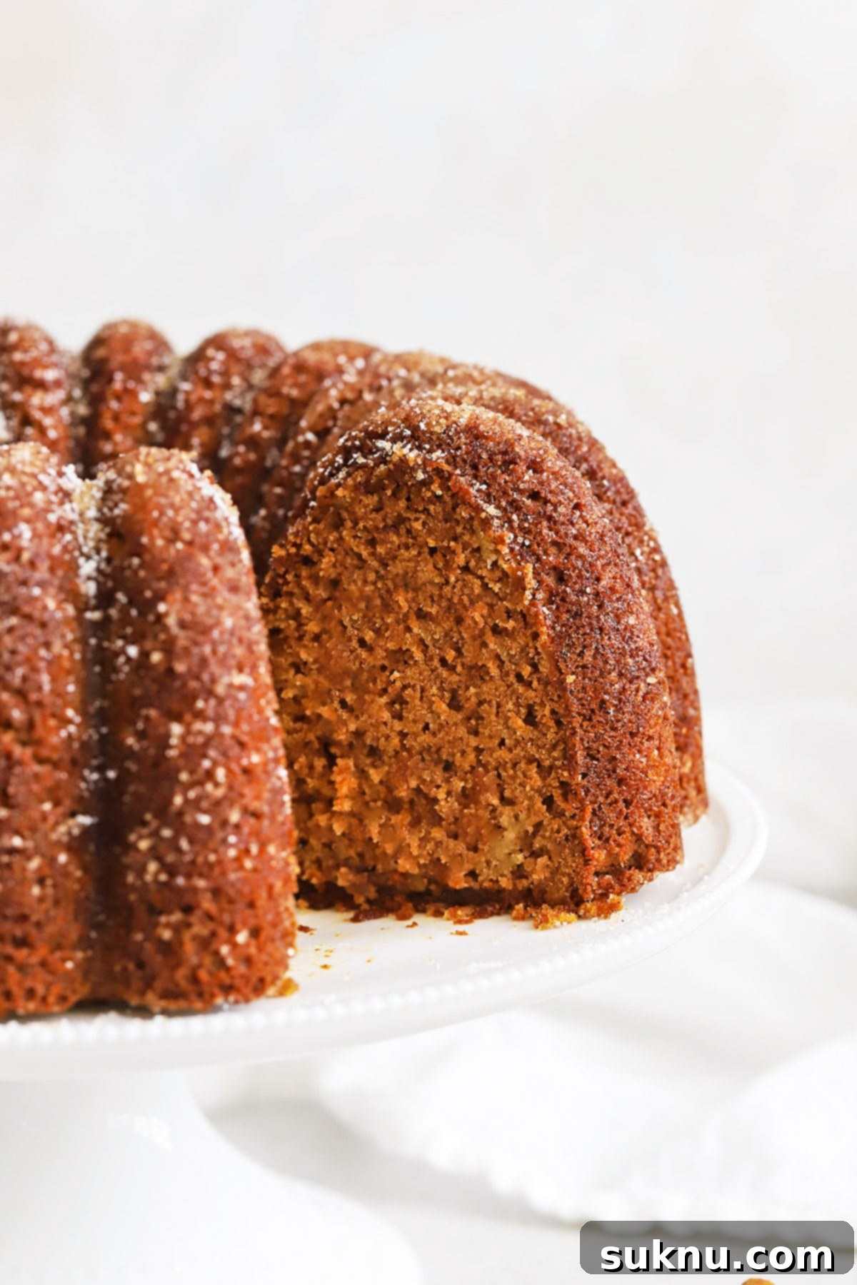 Gluten-Free Apple Spice Bundt Cake with a slice cut out, revealing a gorgeous tender center and apple pieces.