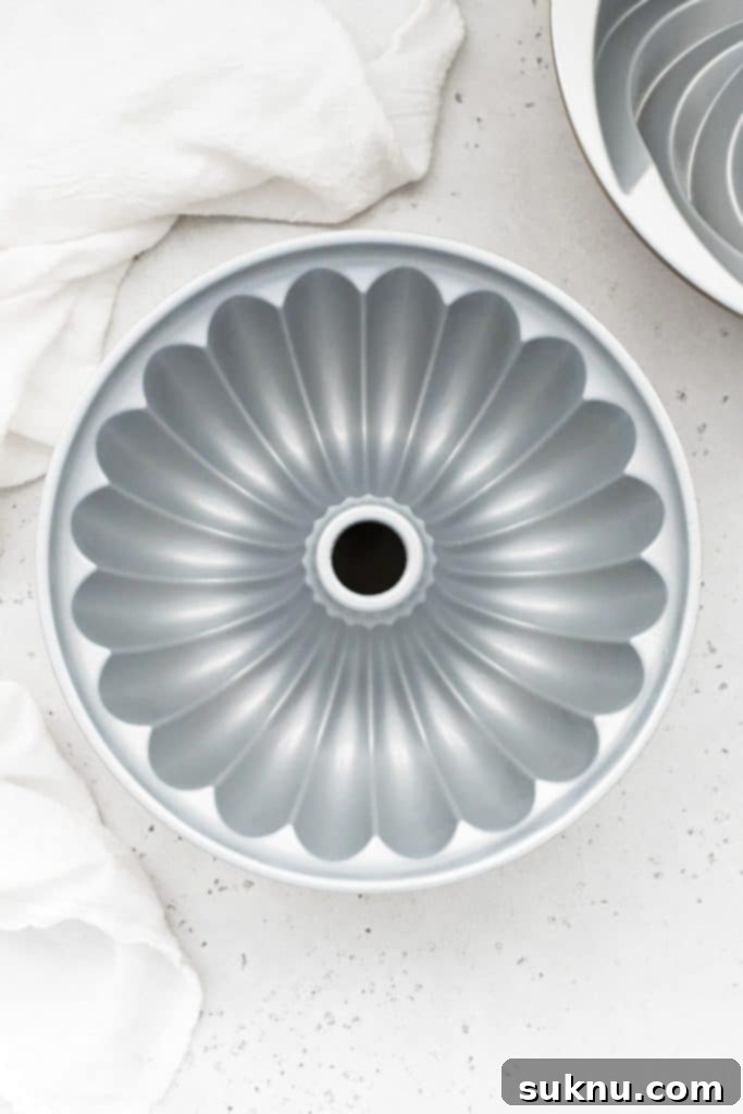 Overhead view demonstrating how to properly grease a bundt pan, ensuring every crevice is coated.