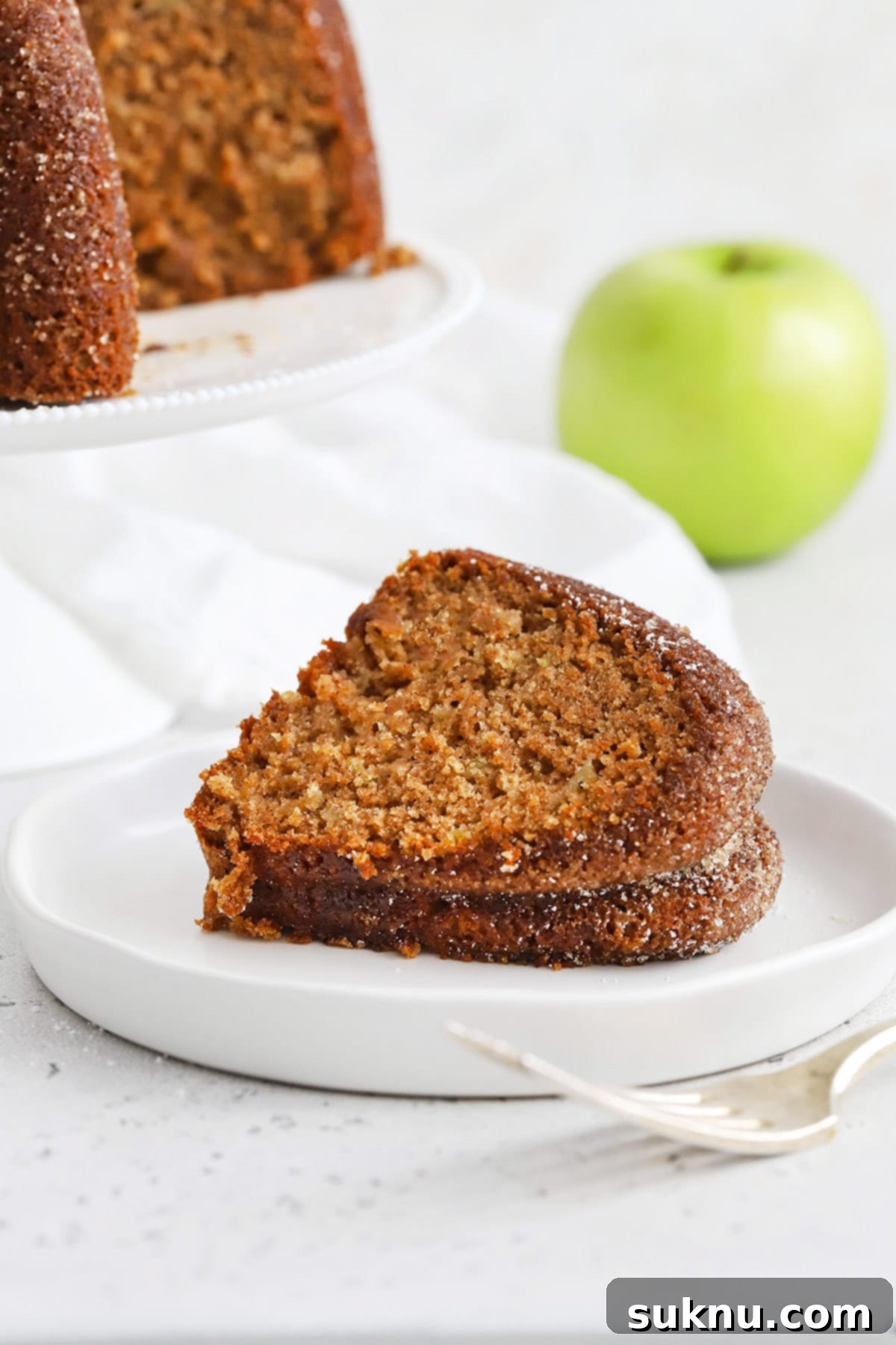 A slice of gluten-free apple spice bundt cake presented on a simple white plate, ready to be enjoyed.
