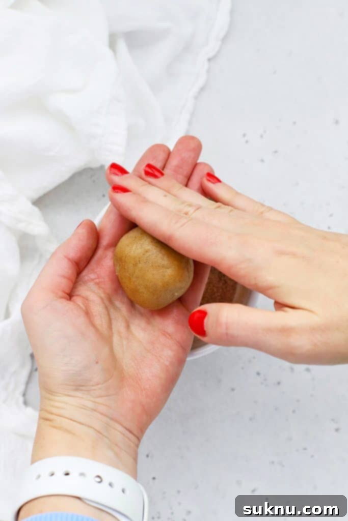 Folding gluten-free snickerdoodle cookie dough around half of a caramel