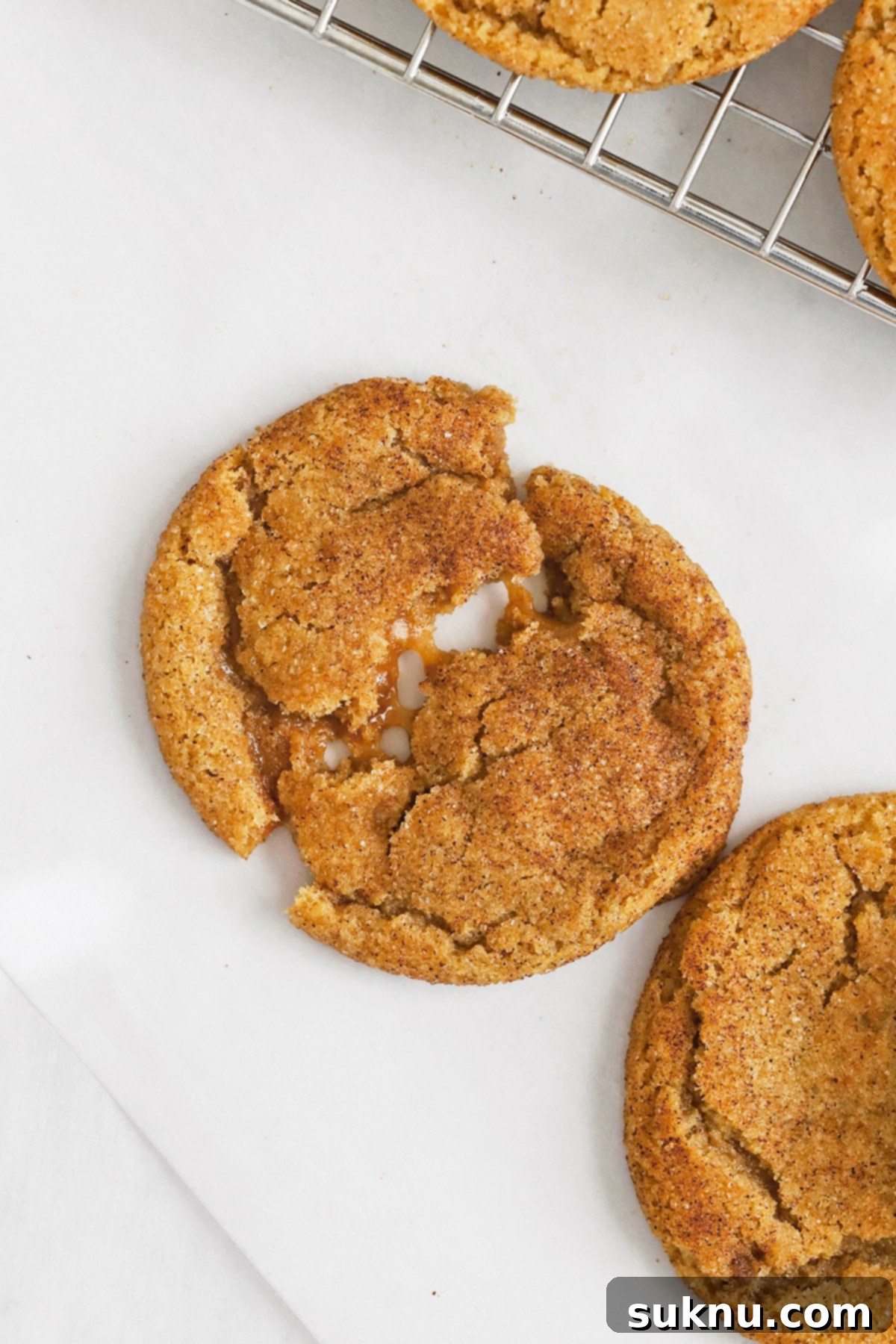 Pulling apart a gluten-free brown butter caramel snickerdoodle cookie, revealing gooey caramel in the center