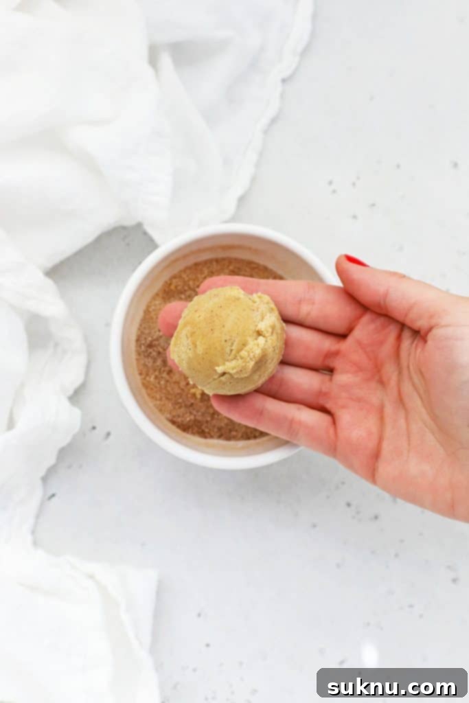 Getting ready to Fold gluten-free snickerdoodle cookie dough around half of a caramel