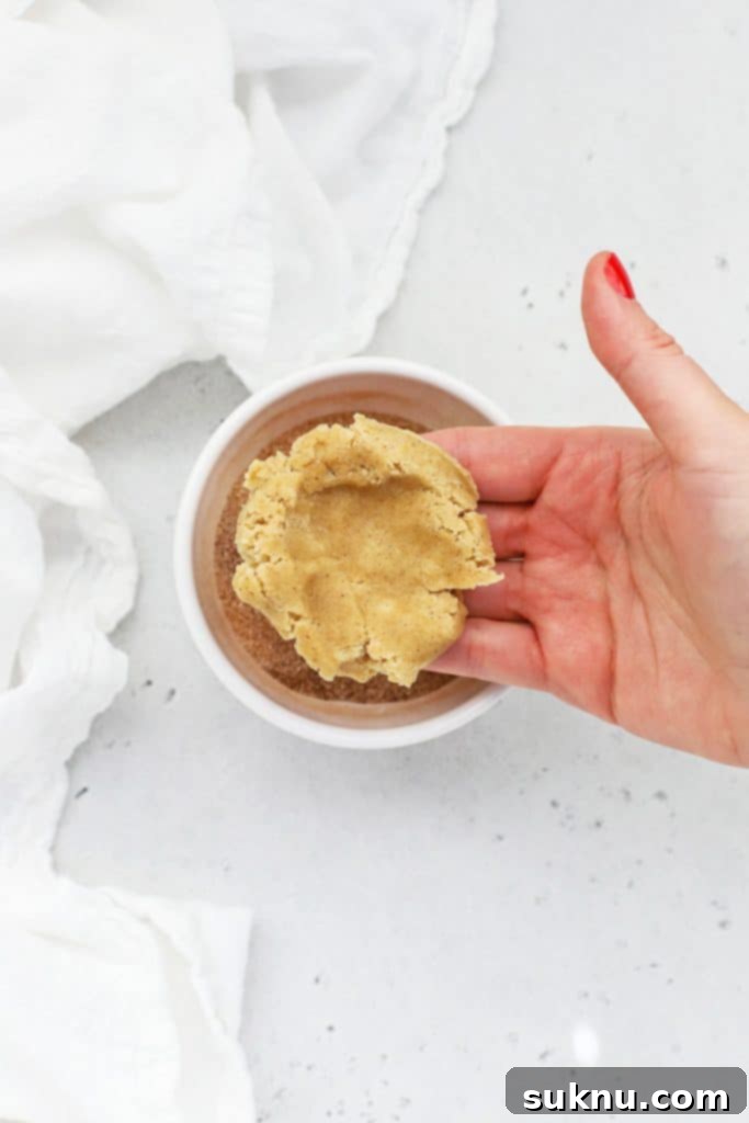 Folding gluten-free snickerdoodle cookie dough around half of a caramel