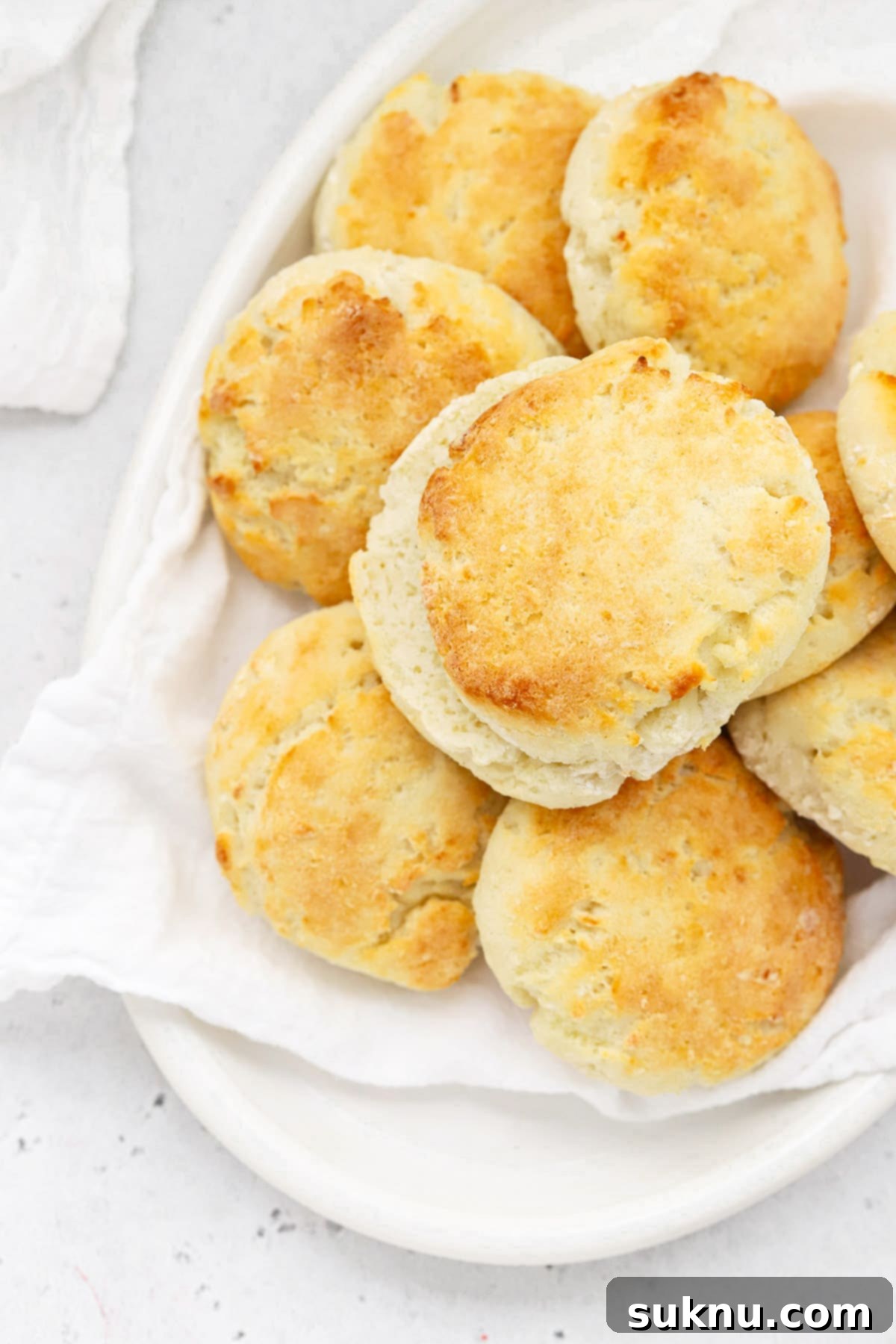 A beautiful arrangement of golden-brown gluten-free biscuits on a pristine white platter, ready to be served.