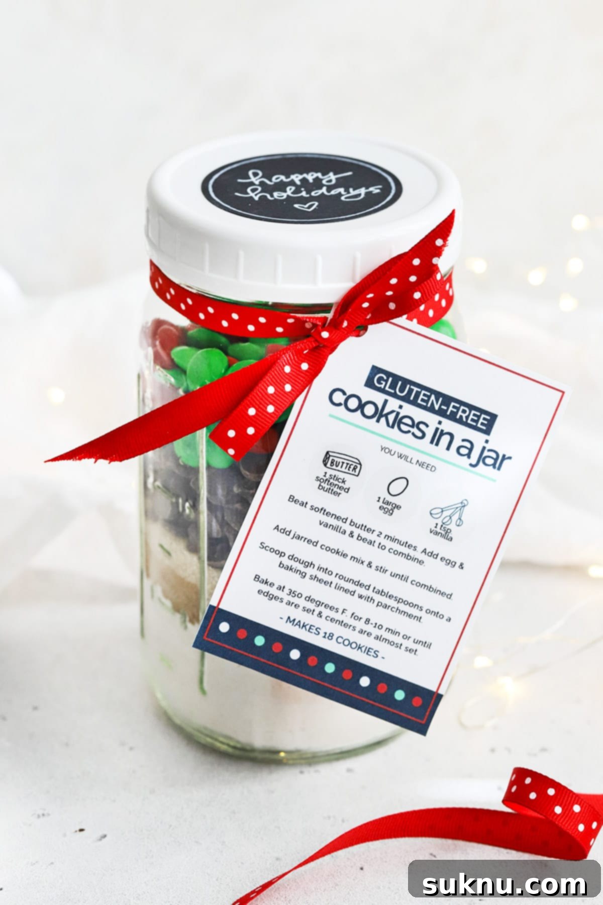 Elegant front view of a gift-ready gluten-free holiday M&M cookie mix in a jar, adorned with a decorative ribbon and a free printable instruction tag.