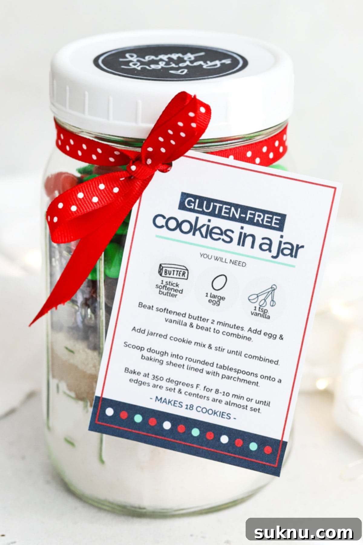 Charming front view of a gluten-free M&M cookie mix in a jar, featuring a festive printable gift tag tied with a ribbon, ideal for holiday gifting.