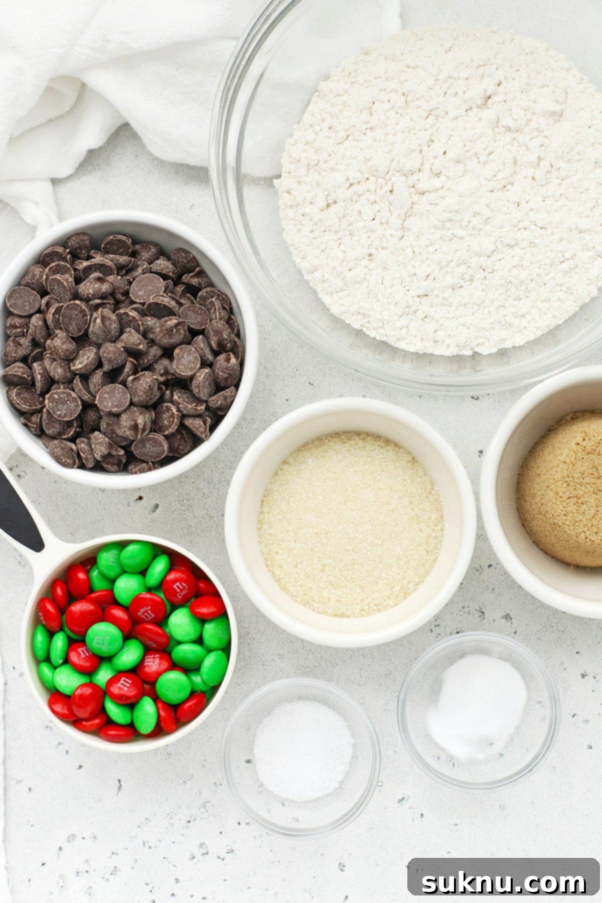 Overhead shot of all ingredients neatly laid out for making gluten-free chocolate chip M&M cookies in a jar, showcasing flour, sugars, chocolate chips, and M&Ms.