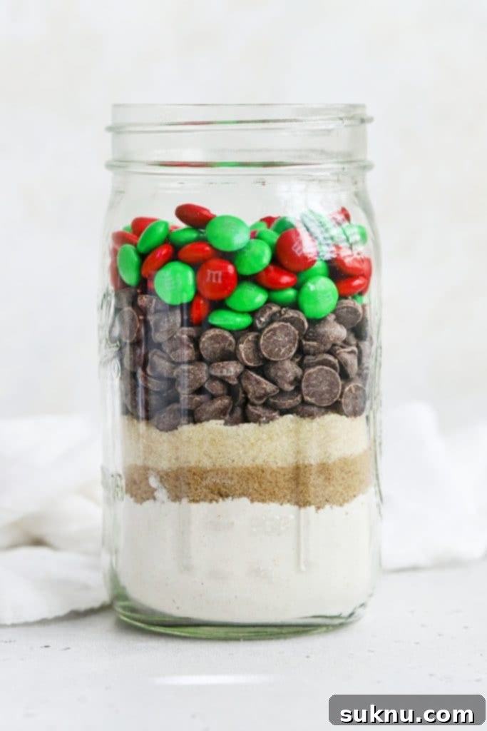 Detailed side view of a gluten-free M&M cookie mix jar, clearly displaying the distinct, colorful layers of flour, sugars, chocolate chips, and M&Ms.