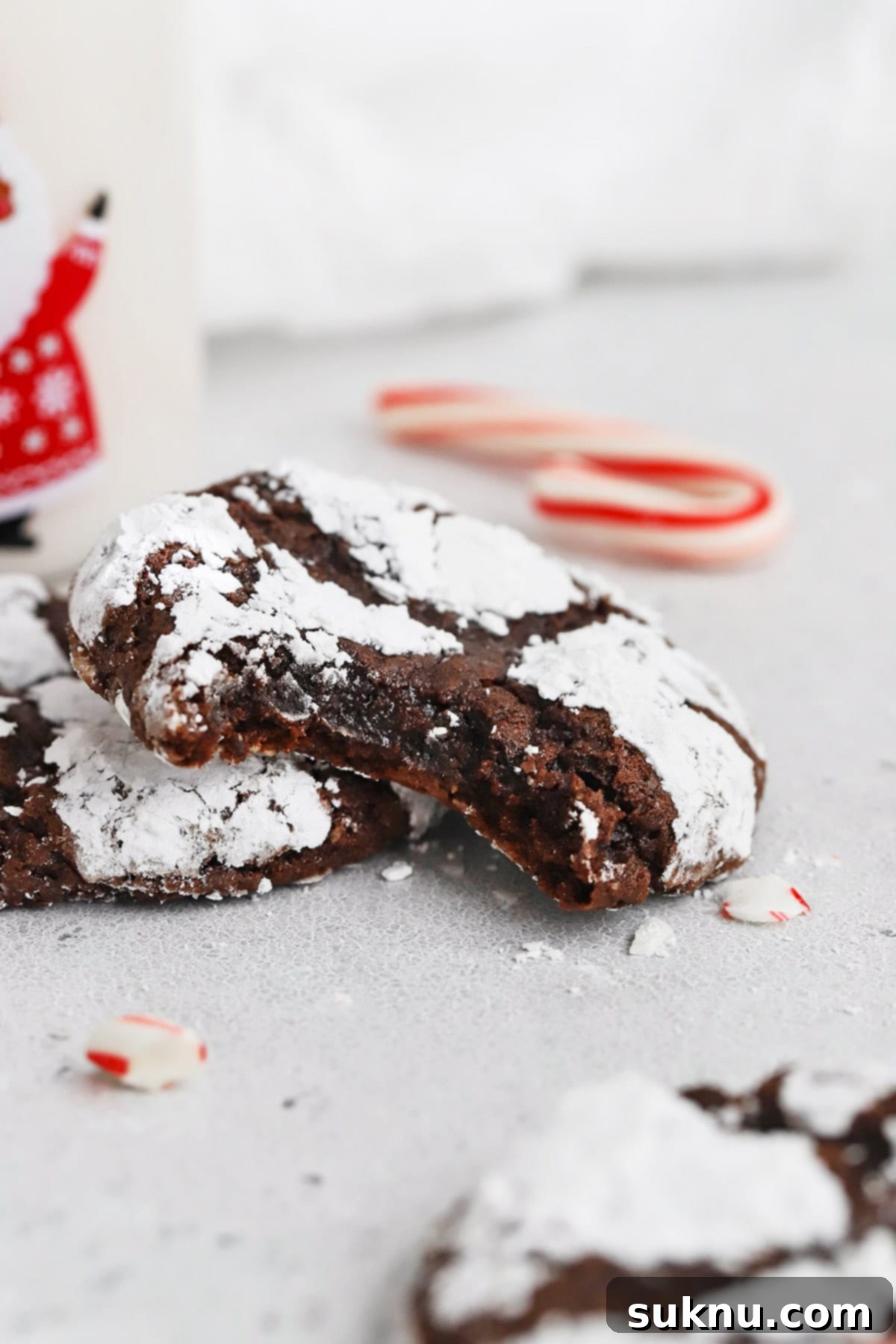 Front view of gluten-free peppermint chocolate crinkle cookies, with one cookie showing a delicious bite taken out, revealing its soft, fudgy center.