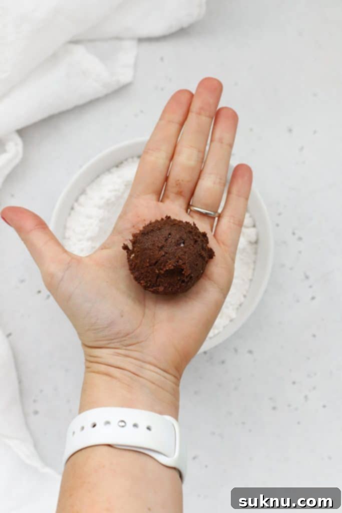 Scooped ball of peppermint chocolate crinkle cookie dough, perfectly portioned and ready for coating.