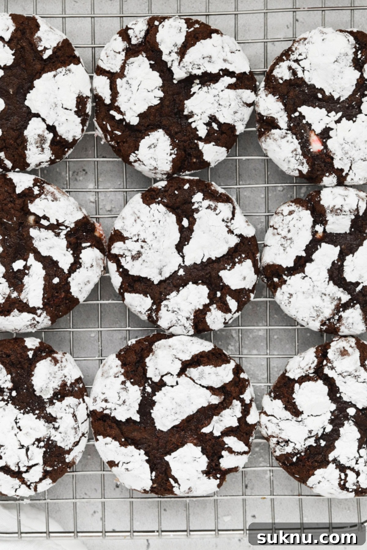 Overhead view of gluten-free peppermint chocolate crinkle cookies cooling on a wire rack, showcasing their distinctive crackled tops.