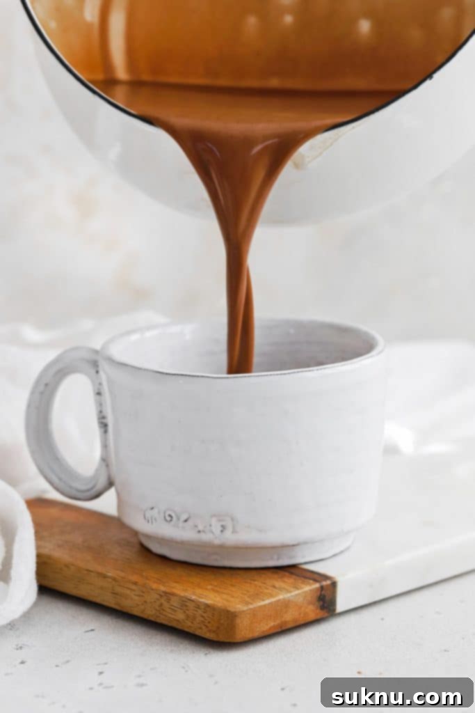 Peppermint Dream Vegan Cocoa 7 A close-up, front view of rich, creamy vegan peppermint hot chocolate being poured into a mug, ready to be enjoyed.