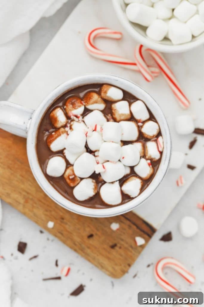 Peppermint Dream Vegan Cocoa 8 Overhead shot of a steaming mug filled with vegan peppermint hot chocolate, generously topped with fluffy white marshmallows, creating a perfect cozy scene.