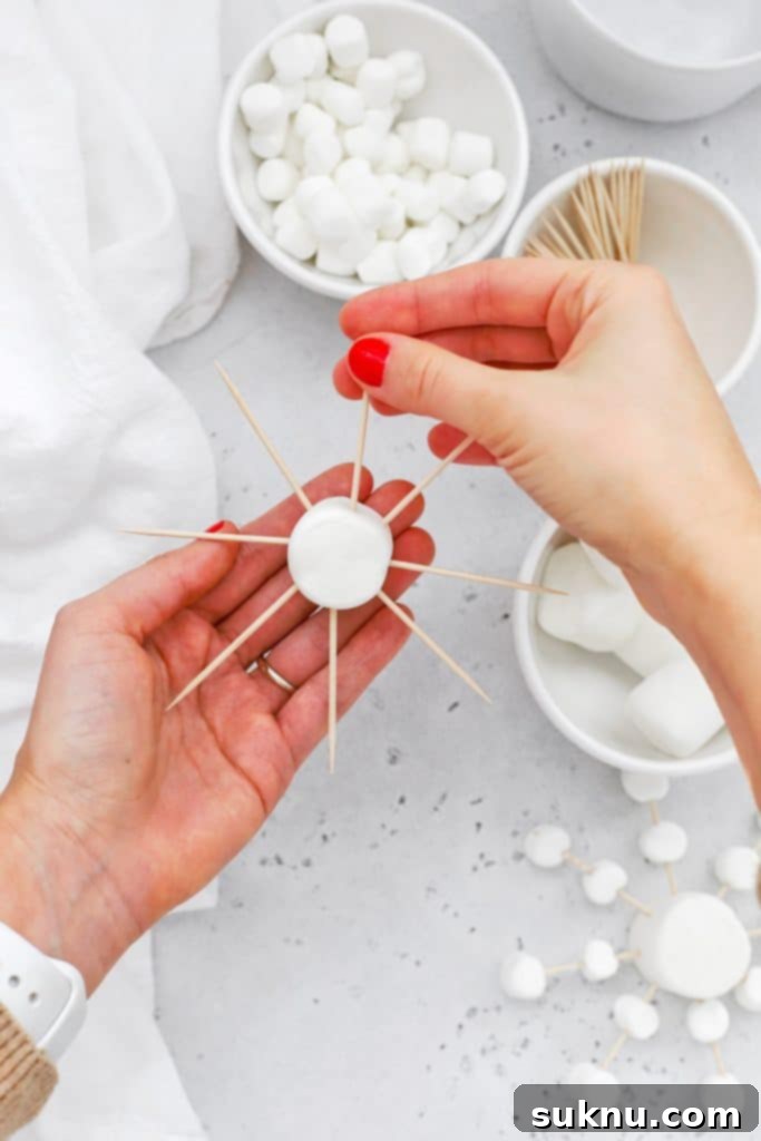 Marshmallow Snowflake Magic 7 Detailed image showing mini marshmallows being added to the toothpick arms of the snowflake.