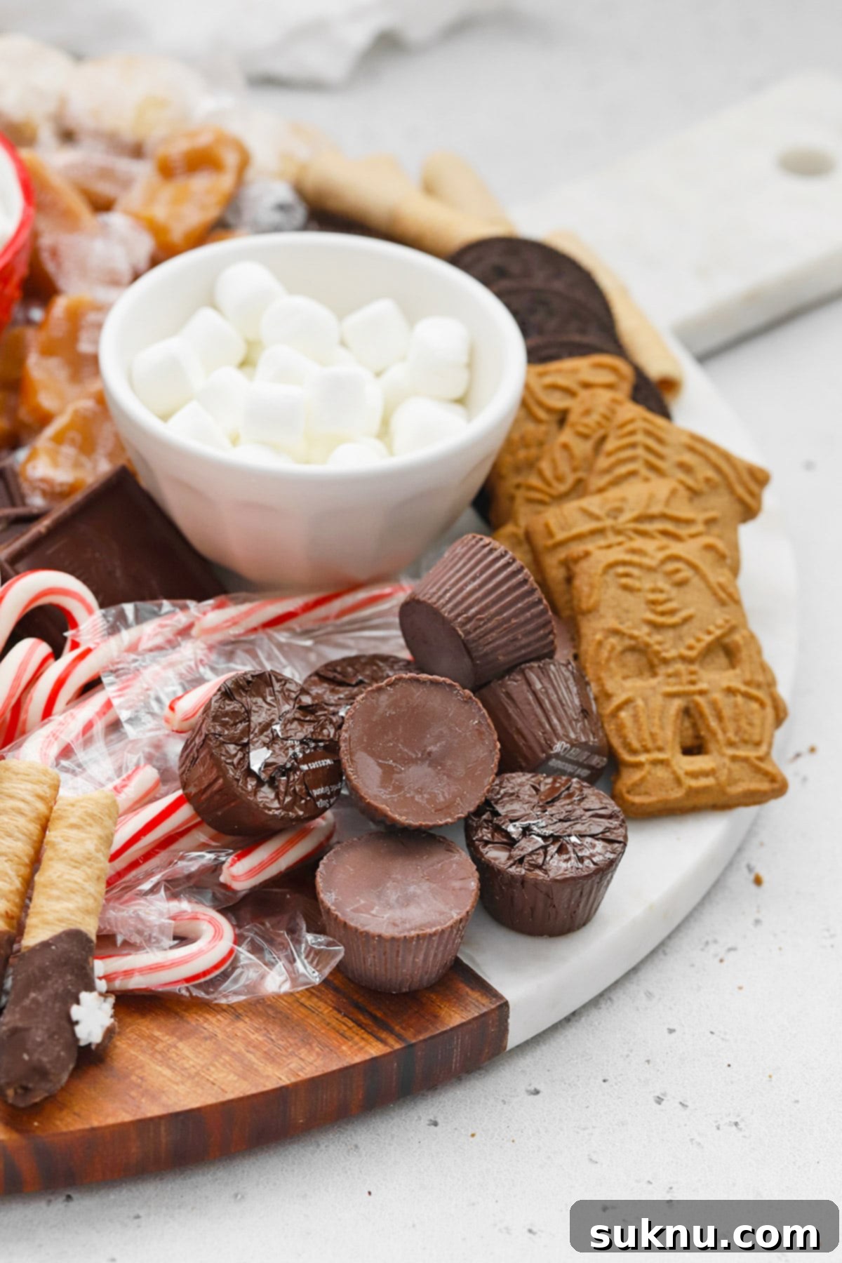A detailed front view of an inviting gluten-free hot chocolate charcuterie board, showcasing an assortment of marshmallows, candies, and cookies arranged artfully.