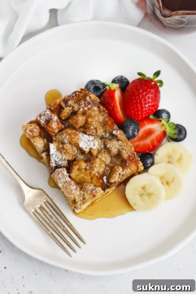 Holiday Gluten Free Eggnog French Toast Bake 13 Overhead view of a perfect slice of gluten-free eggnog french toast casserole, garnished with powdered sugar and a drizzle of maple syrup