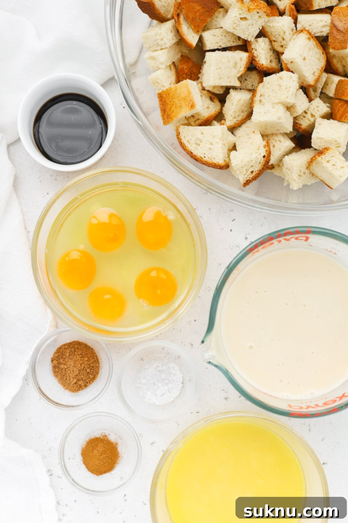 Holiday Gluten Free Eggnog French Toast Bake 3 A collection of ingredients laid out, including gluten-free bread, eggnog, eggs, vanilla, and spices, ready for making gluten-free eggnog french toast casserole