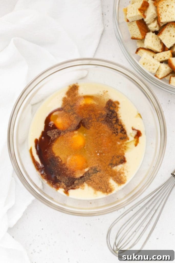 Holiday Gluten Free Eggnog French Toast Bake 4 Ingredients for eggnog custard laid out, including a bowl of eggs, a jug of eggnog, vanilla, and spices, ready to be whisked for the gluten-free eggnog french toast casserole