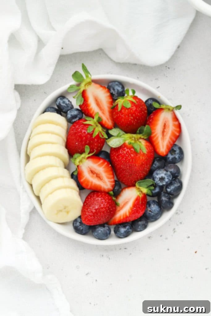 Holiday Gluten Free Eggnog French Toast Bake 10 overhead view of a plate of fresh strawberries, blueberries, and sliced bananas, perfect for topping a breakfast casserole