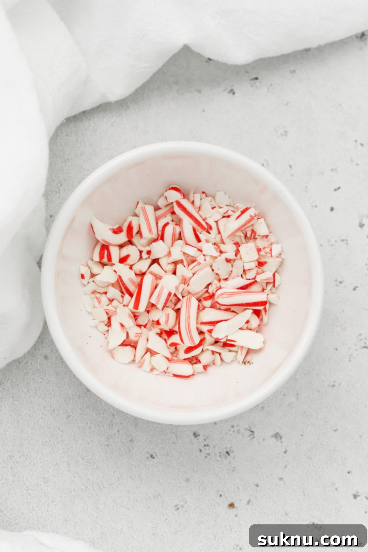 Bowl of vibrantly crushed candy canes, a key topping ingredient for holiday brownie bites, showcasing various textures.