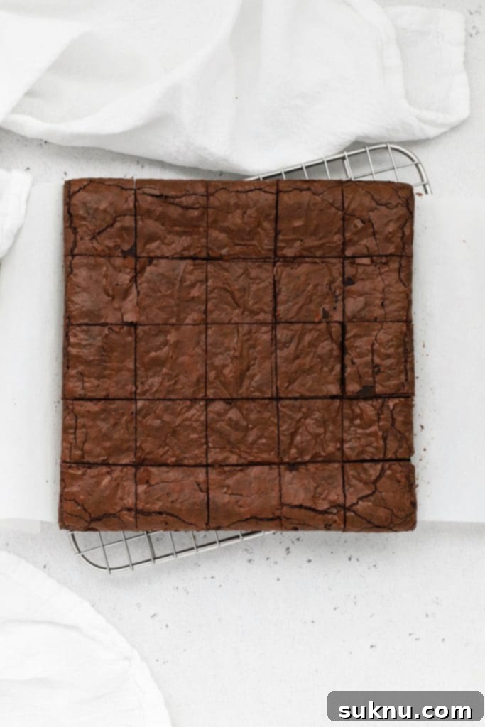 Overhead view of a freshly baked gluten-free brownie sheet, precisely cut into small, uniform squares, ready to be dipped and decorated.