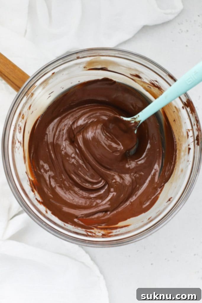 Melted dark chocolate in a double boiler, showing its smooth, glossy, and perfectly fluid texture, prepared for dipping peppermint brownie bites.