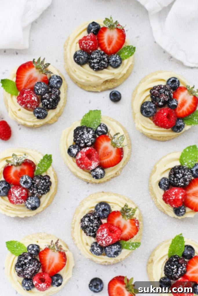 Brown Sugar Cream Cheese Fruit Dream 13 Overhead view of gluten-free fruit pizza cookies topped with cream cheese frosting, fresh berries, and powdered sugar