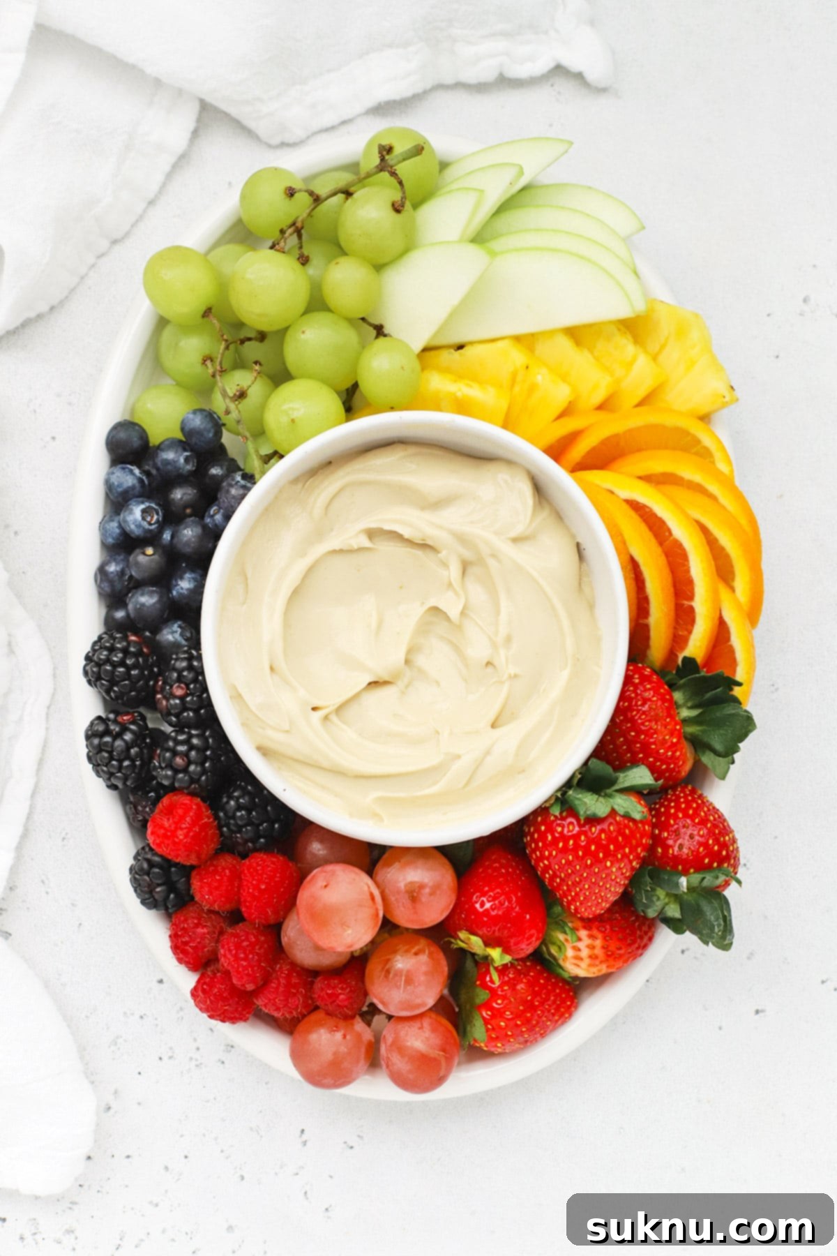 Brown Sugar Cream Cheese Fruit Dream 8 Overhead shot of Brown Sugar Cream Cheese Fruit Dip surrounded by a colorful assortment of fresh fruit on a white platter