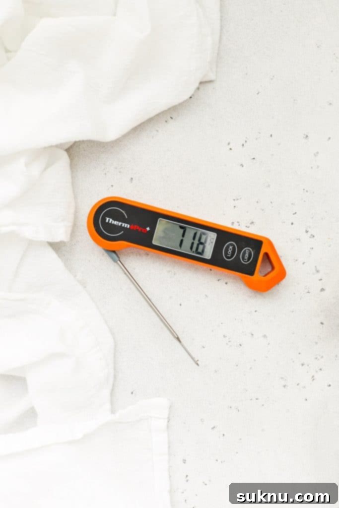 Instant read thermometer being inserted into a loaf of banana bread to check internal temperature.