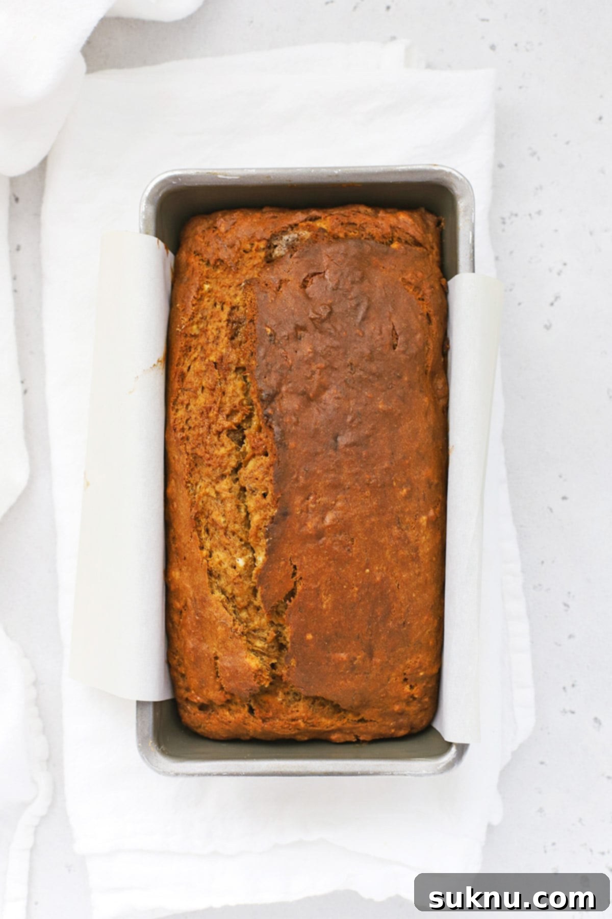 Overhead view of a perfectly baked loaf of gluten-free brown butter banana bread, showing a golden crust.