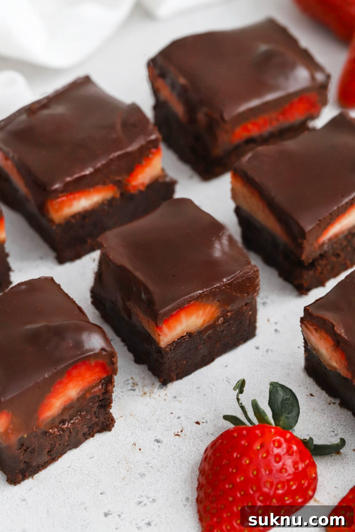 Front view of gluten-free strawberry brownies with fresh strawberries and chocolate ganache, ready to be served for a special occasion like Valentine's Day.
