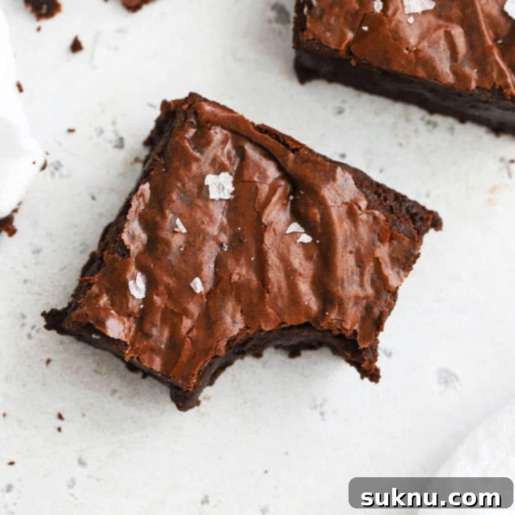 Overhead view of fudgy gluten-free brown butter brownies, cut into neat squares, showcasing their dense texture and crackly top.