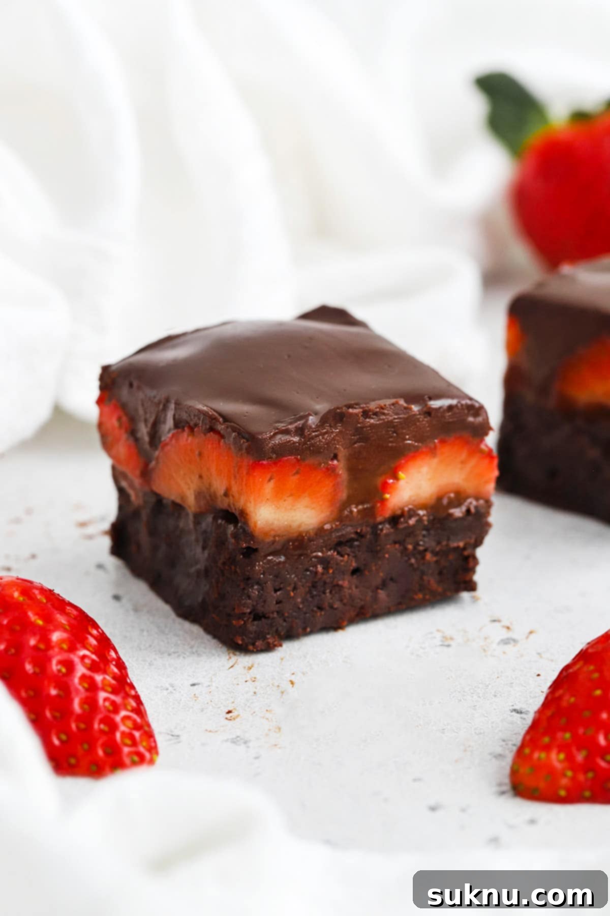 Front view of gluten-free strawberry brownies with fresh strawberries and chocolate ganache, beautifully presented on a serving platter, ready for a gathering.