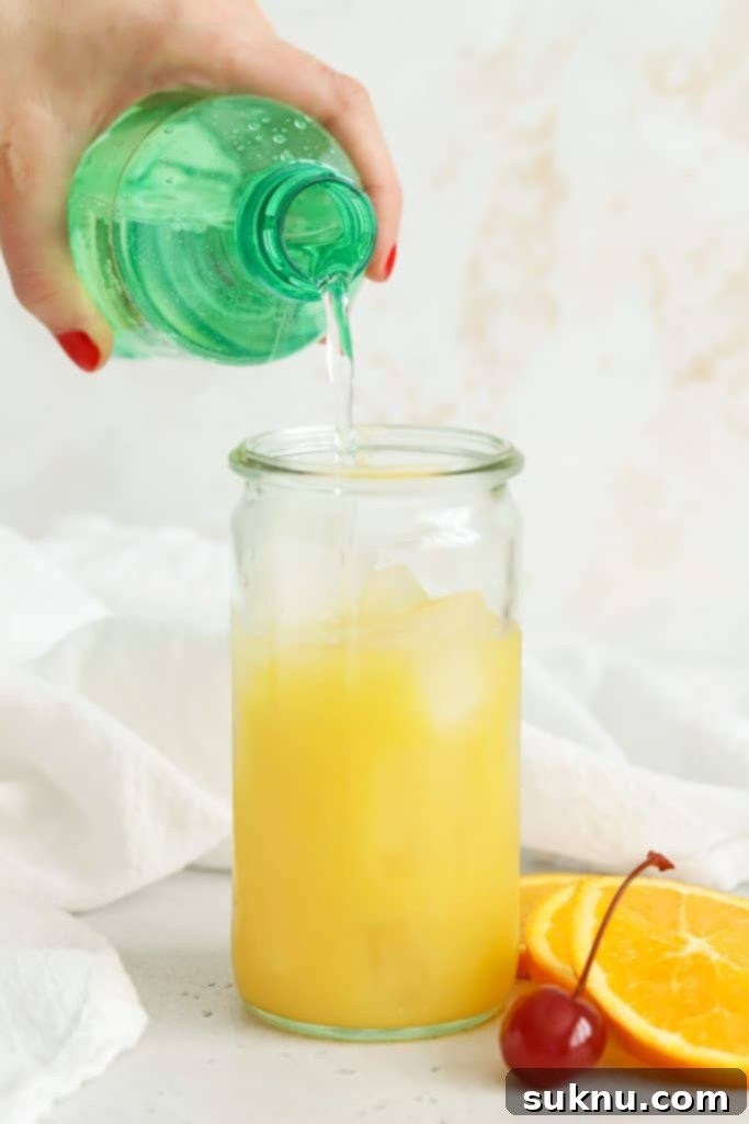 Adding lemon-lime soda to orange juice and ice for a virgin sunrise mocktail