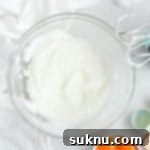 Mastering Whipped Egg Whites: Stiff and Soft Peak Techniques 12 Egg whites whipped to stiff peaks in a glass bowl