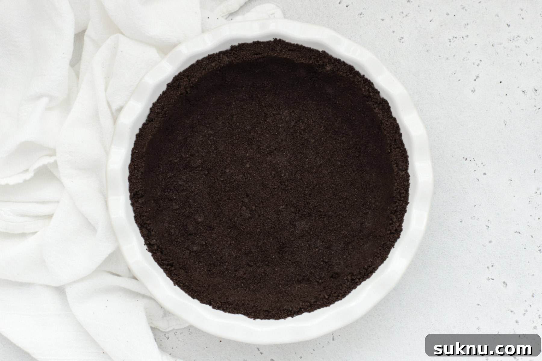 Overhead view of gluten-free oreo crust in a white pie pan, beautifully prepared