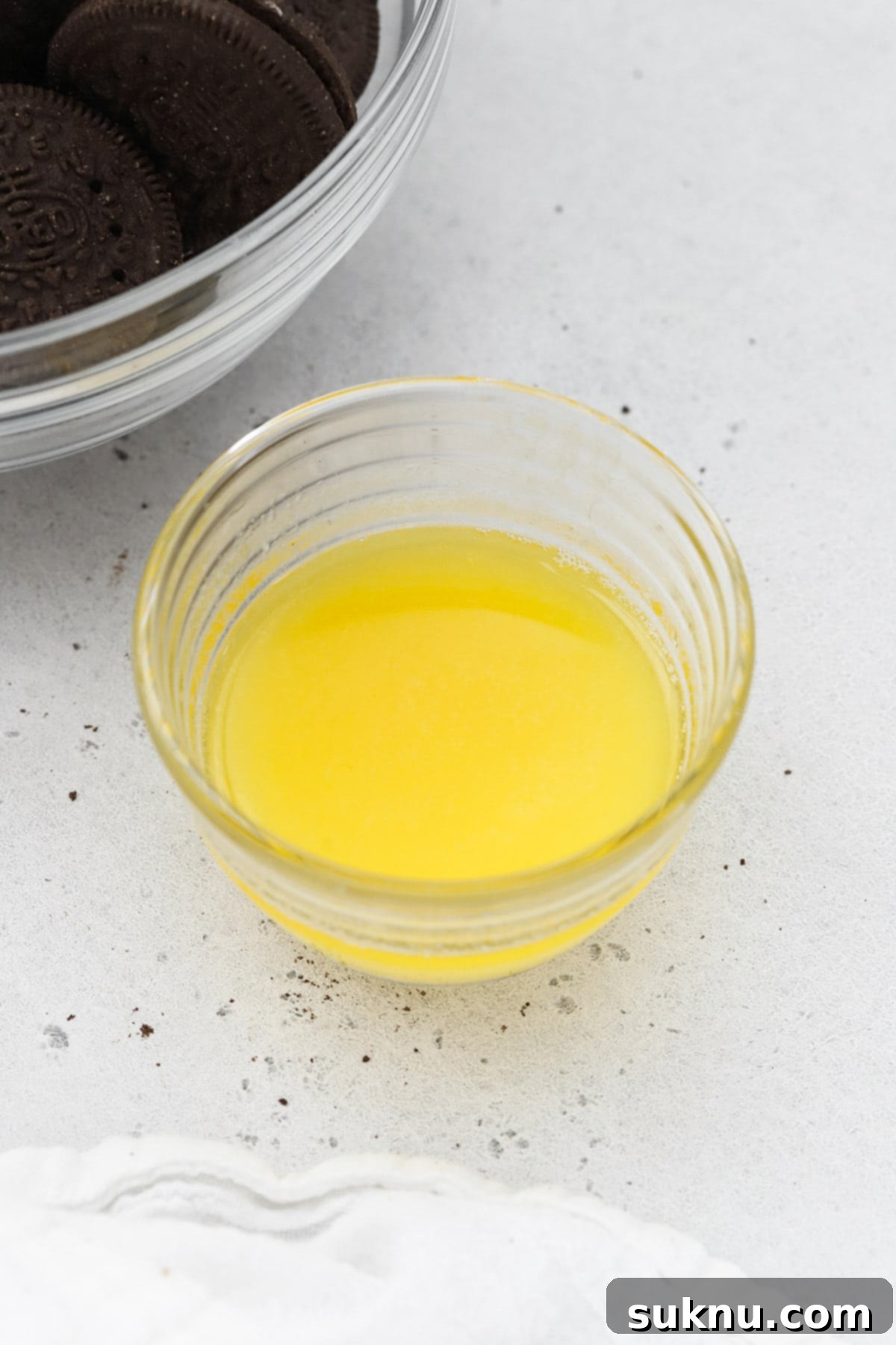 A bowl of melted butter, essential for binding the gluten-free chocolate cookie crumbs