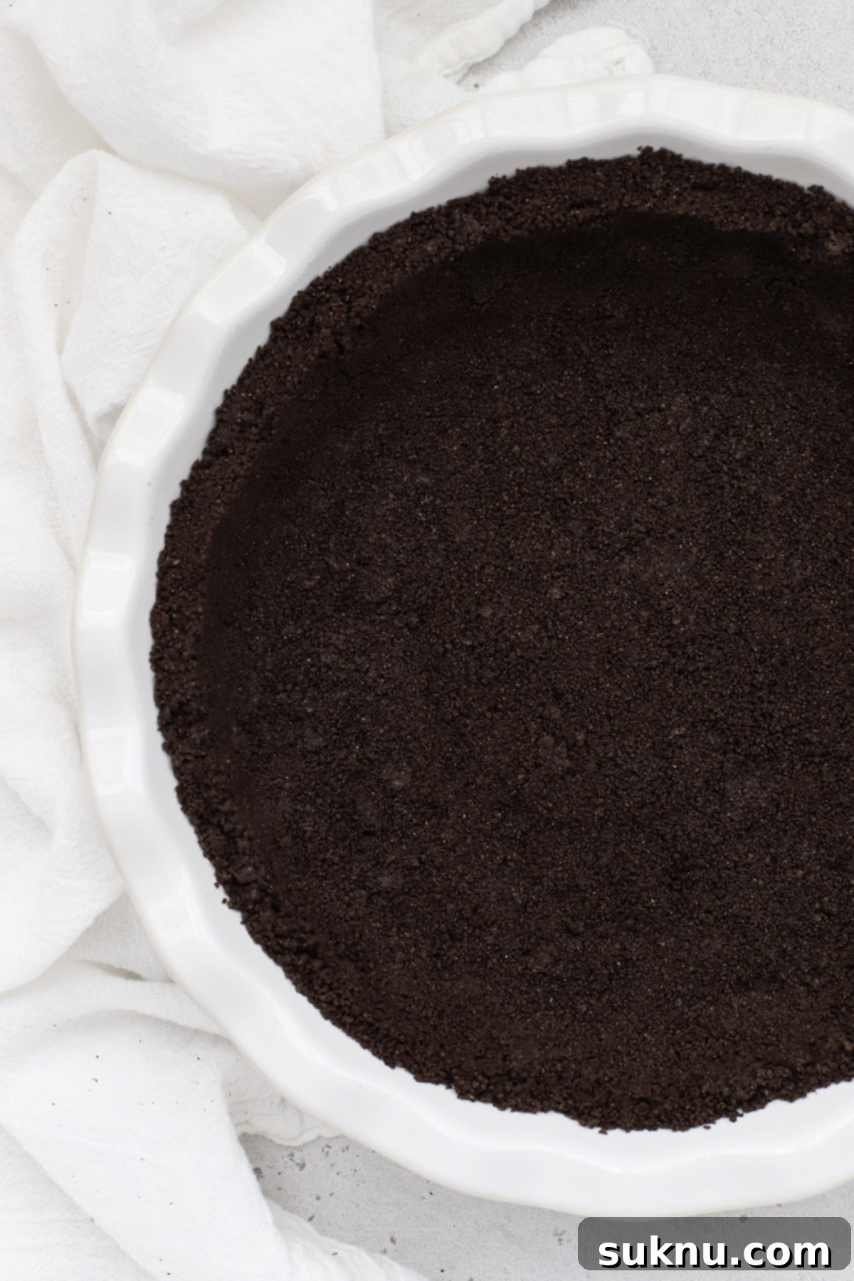 Another overhead view of the gluten-free Oreo crust in a white pie pan, showcasing its perfect texture
