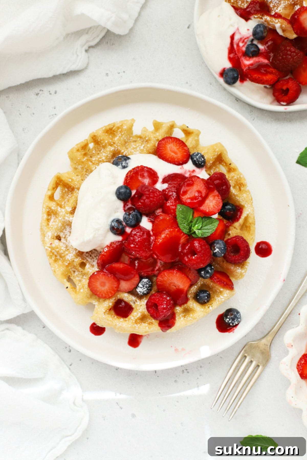 Overhead view of fluffy gluten-free Belgian waffles topped with whipped cream and berries