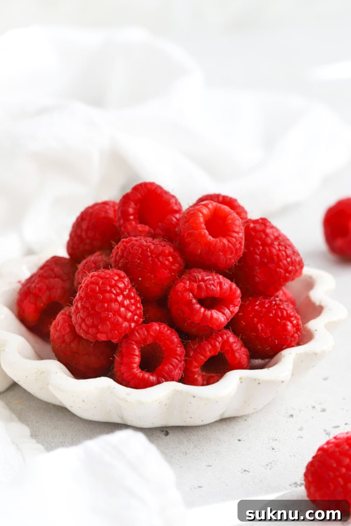 Vibrant Raspberry Coulis 3 Front view of a ruffled white bowl of fresh raspberries