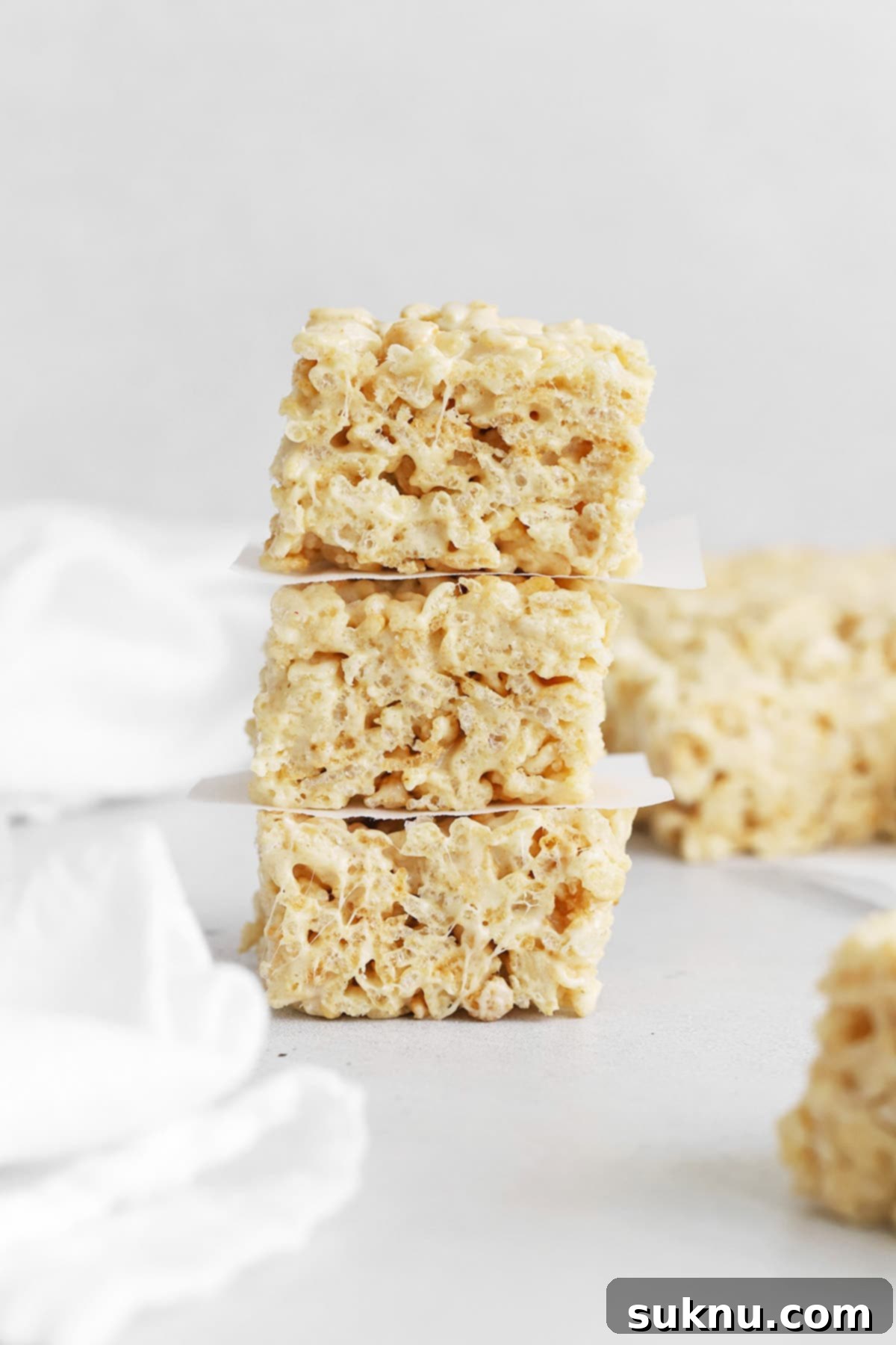 Three perfectly stacked gluten-free brown butter rice krispies treats, glistening with sea salt, ready to be enjoyed.